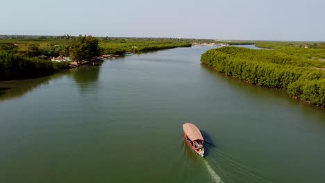 Atemberaubende-Luftaufnahme-Eines-Lokalen-Touristenbootes,-Das-Auf-Dem-Fluss-Gambia-Segelt,-Mit-Vorbeifliegenden-Möwen-In-Kartong