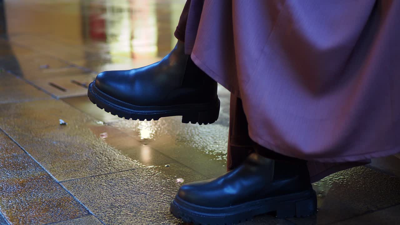 primer plano de botas negras en el pavimento mojado