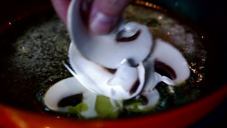 sliced mushrooms are frying in a hot red pan