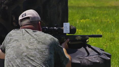 skilled sharpshooter aiming rifle with handwritten scoring at shooting range in leach, oklahoma