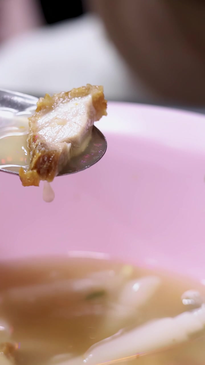 Slow Motion of Crispy Pork Being Lifted from Noodle Soup