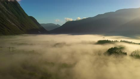 morning mist over the valley among the mountains in the sunlight. fog and beautiful nature of norway aerial footage.
