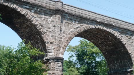 Water-reflections-of-sunlight-under-stone-train-bridge,-Wissahickon-Creek