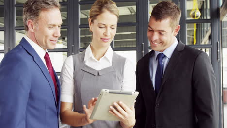 Business-people-talking-together-while-looking-tablet