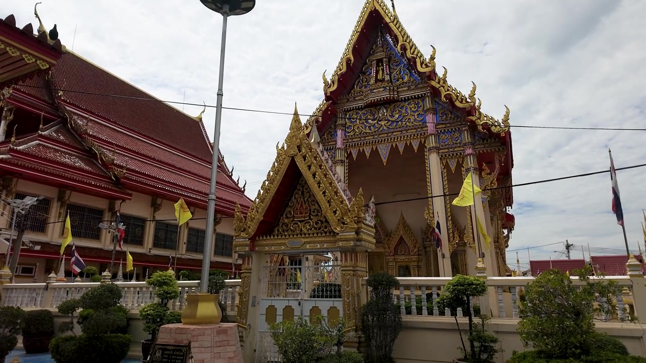 Inquadratura in tilt-down di architettura tradizionale di un tempio thailandese con sculture dorate sotto cieli nuvolosi