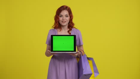 woman holding laptop and shopping bags in front of green screen