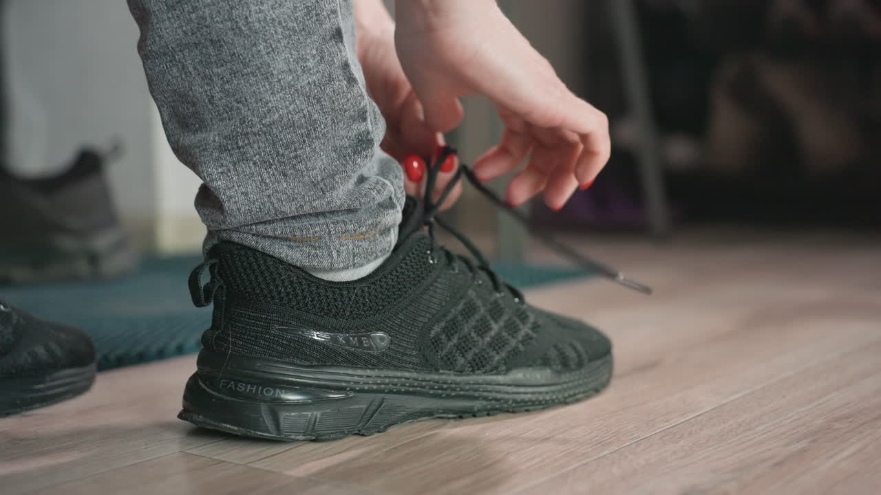 Tying Sneakers Before Workout, Person Fastening Laces On Athletic Shoes Ready For Exercise Session, Closeup Of Hands Securing Shoe Laces By Entryway As Preparation For Physical Activity