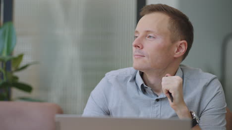 young thoughtful business man thinking of problem solution working on laptop. serious doubtful male professional looking away at laptop considering market risks making difficult decision