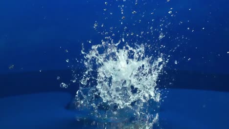 salpicaduras de agua en cámara lenta en el fondo de la pantalla azul