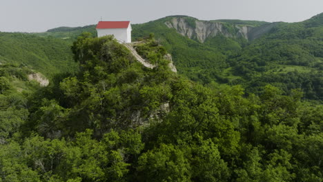 simple, orthodox tsveri church surrounded with green, forested valley