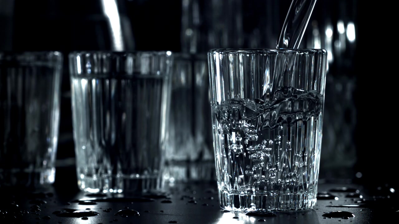 Klart vand hældes ned i et glas i slowmotion