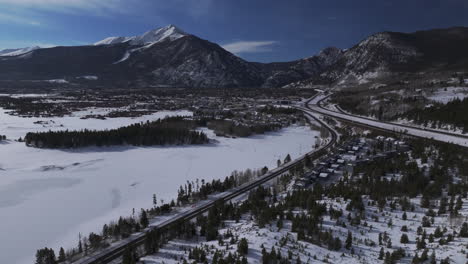 downtown frisco i70 colorado aerial cinematic drone lake dillon marina summit cove sun cloudy snowy winter morning view silverthorne ten mile range breckenridge calm unfrozen ice forward reveal