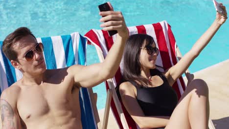 Man-and-woman-taking-self-portraits-at-pool