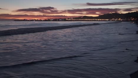 gimbal panning shot of the magical sky reflecting in the gentle waves at twilight on east beach in santa barbara, california. 4k at 48 fps slow motion