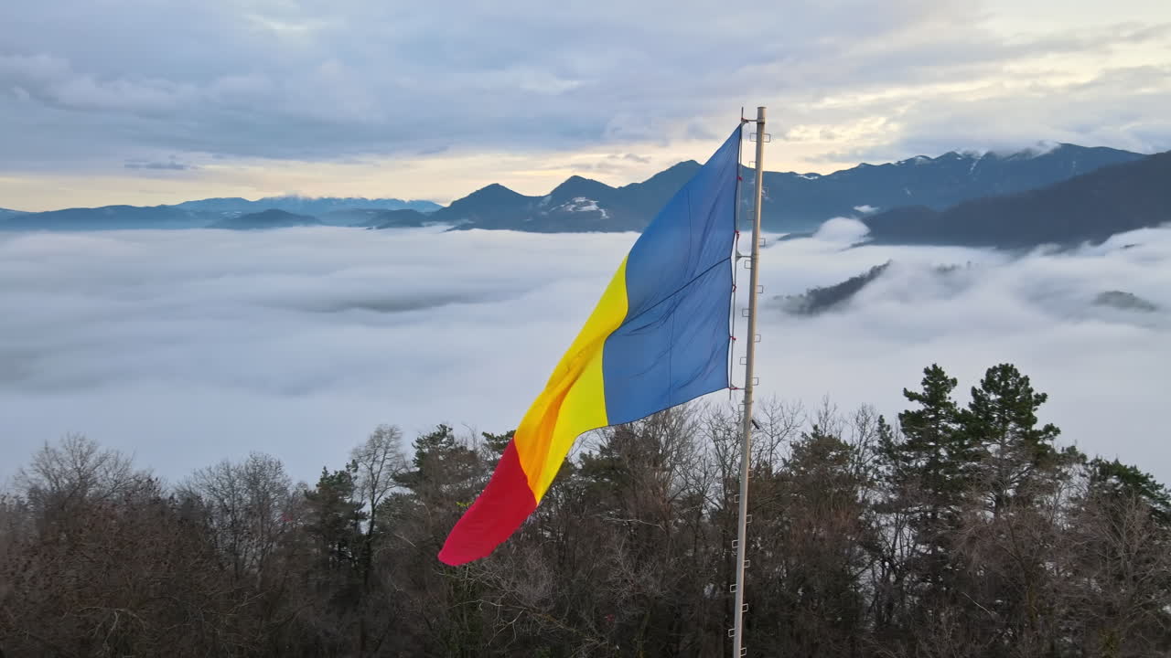 Bandiera nazionale in cima a una collina vicino a Barsov, alberi spogli, nuvole basse, Romania