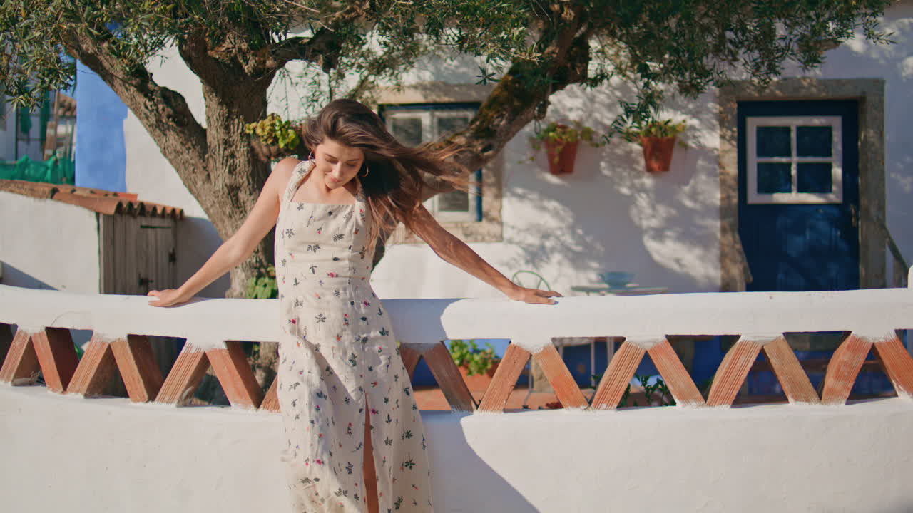 오래된 집 근처의 울타리에 기울어진 빛을 따뜻하게 하는 장난스러운 소녀. 바람을 즐기는 여자