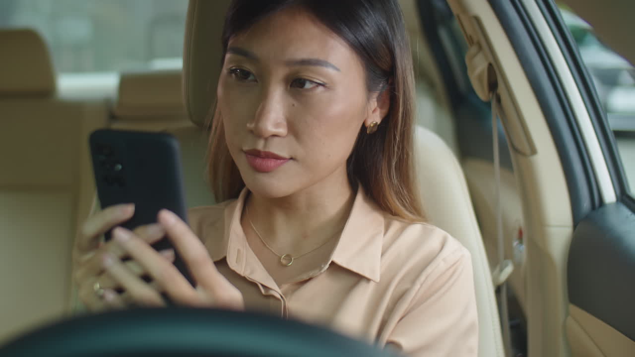 Asian Businesswoman Using Smartphone in Car