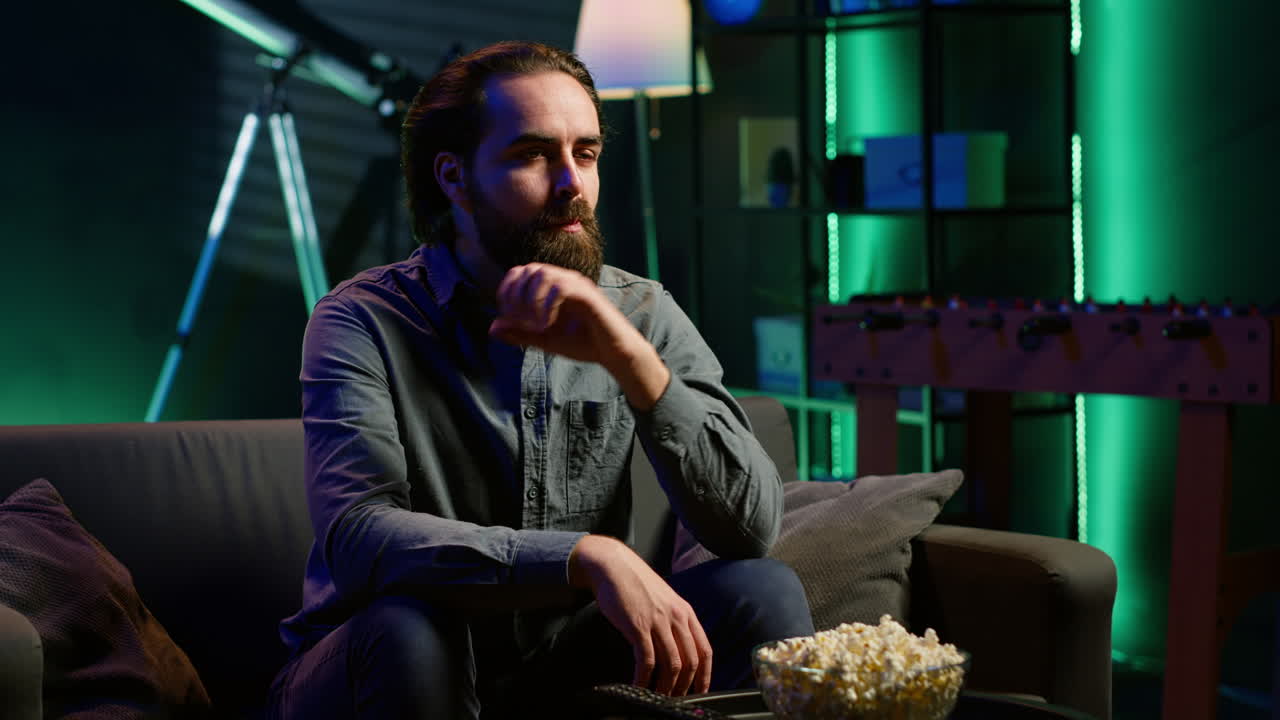 네온 조명 거실에서 간식과 스트리밍 tv 쇼를 먹는 사람