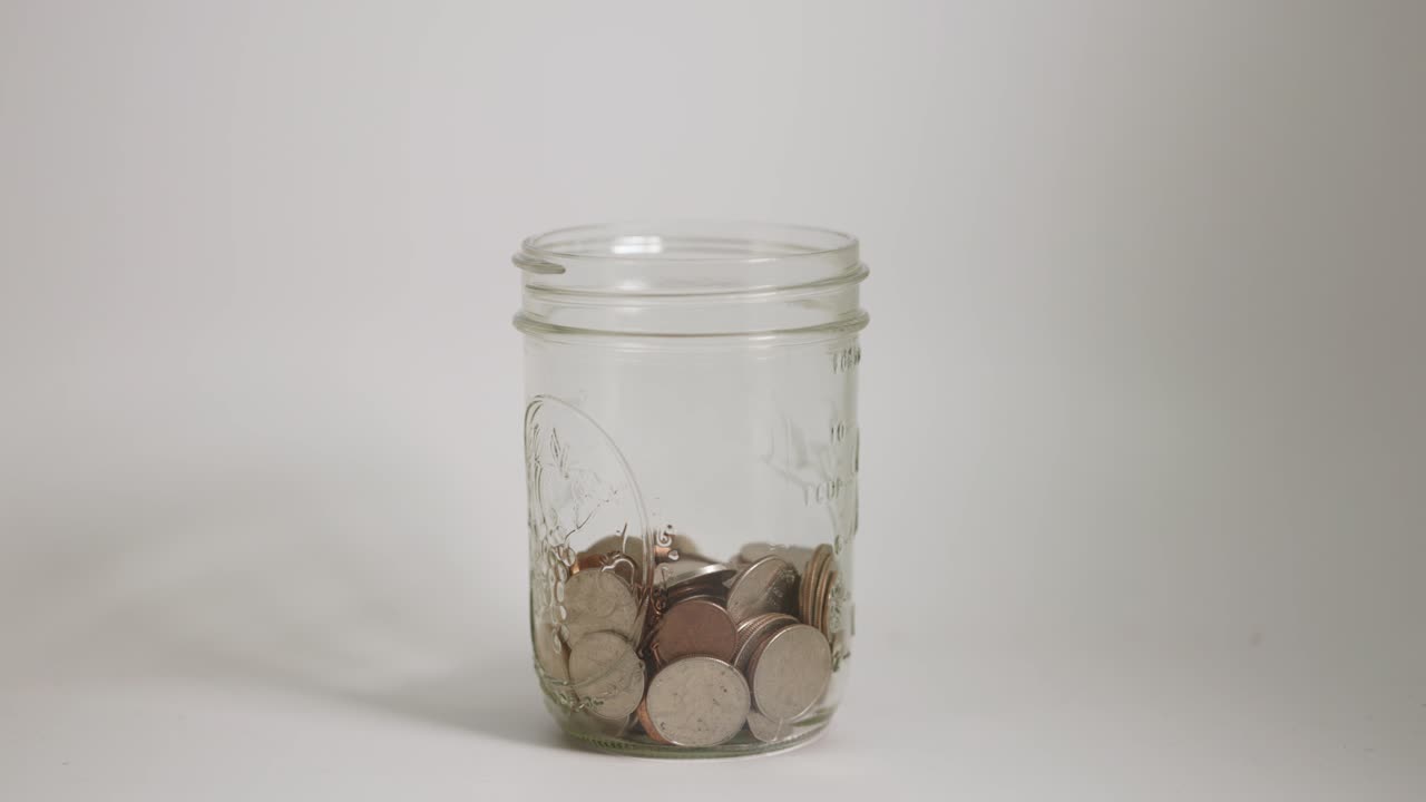 Moedas caindo num frasco de vidro
