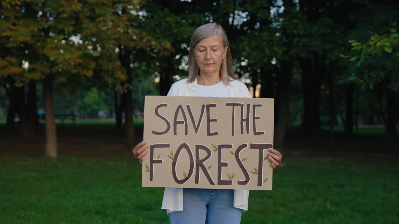 Woman holding a Save the Forest sign in a park