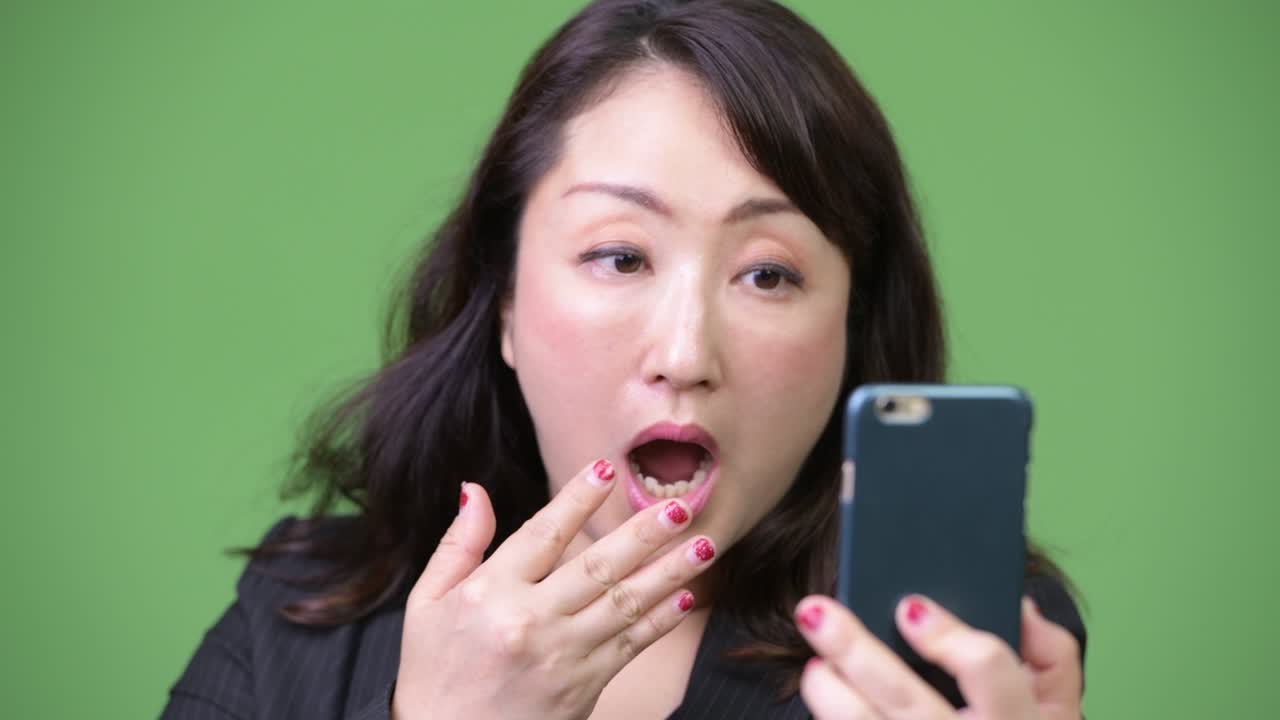 성숙 한 아름다운 아시아 사업가 여자 는 전화 를 사용 하는 동안 충격 을 느끼고 있다