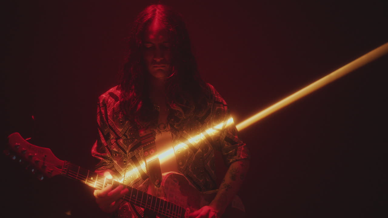 Musician Playing Electric Guitar in Dark Studio with Light Beam