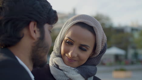 cute woman in hijab looking at boyfriend while dating outdoors