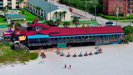 Pompano-Joes-restaurant-in-Destin-Florida-close-up-panning-right-aerial-drone-shot-with-a-view-of-old-98-highway-and-the-white-sand-beach-on-the-Gulf-of-Mexico