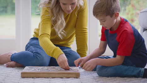 mother and son at home doing jigsaw puzzle on floor of lounge together