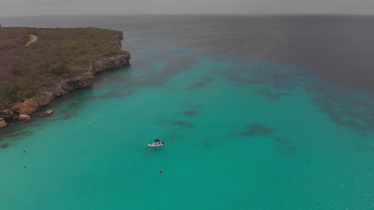 Epic aerial of a tour boat floating incrystal clear waters of Grote Knip on the Dutch Caribbean island of Curacao