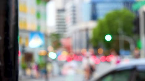 blurry city street with people and vehicles in motion, colorful lights, and modern buildings. daytime, shallow depth of field, static camera, vibrant urban atmosphere