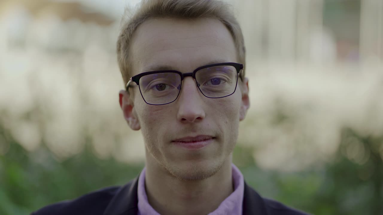 Ragazzo bello con gli occhiali che saluta e parla alla telecamera