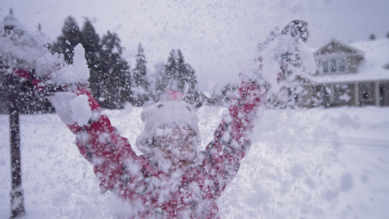 emocionada, feliz niña lanza nieve en el aire en un día frío de invierno, cámara lenta