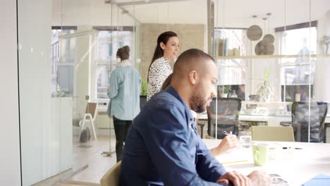 Business-woman-using-tablet-app-showing-3d-printed-model-of-geodesic-dome-walking-through-modern-office-to-diverse-team-meeting