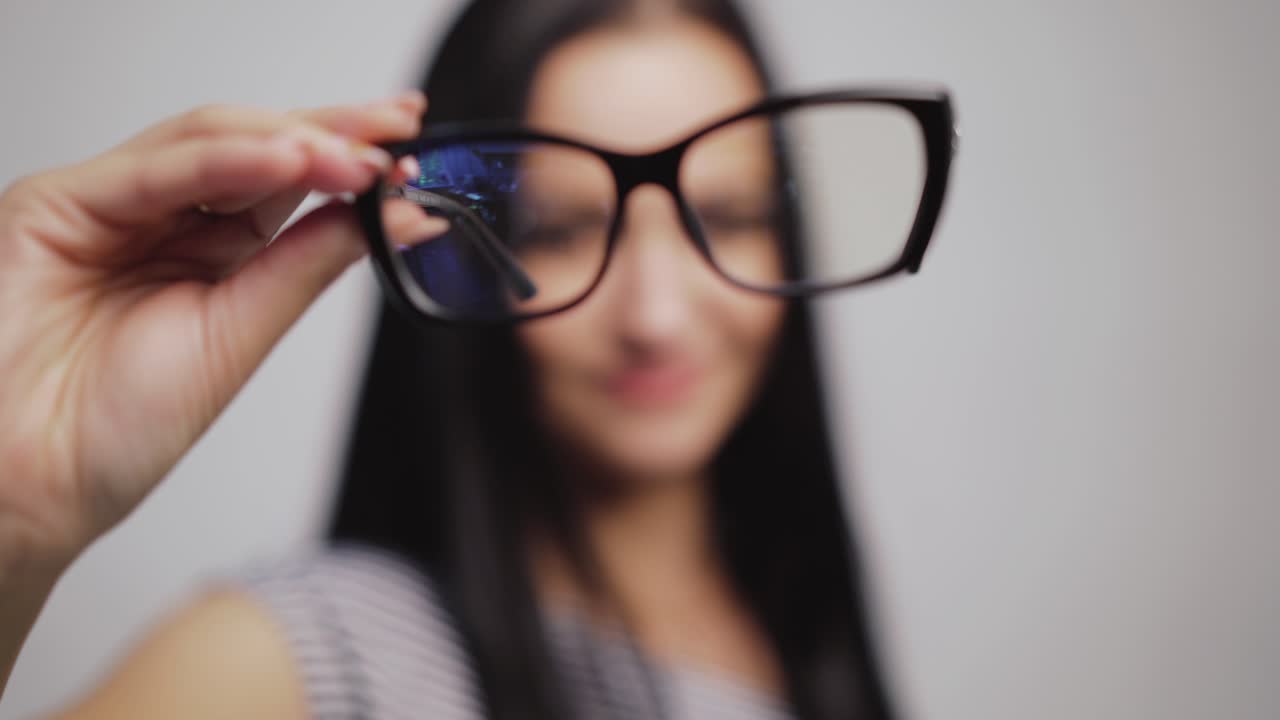 Fashionable eyeglasses close-up on the blurred background of a woman. Woman shows and then puts on new glasses in black rim.