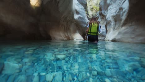 vista medio subacuática de la mujer caminando en el agua en el cañón