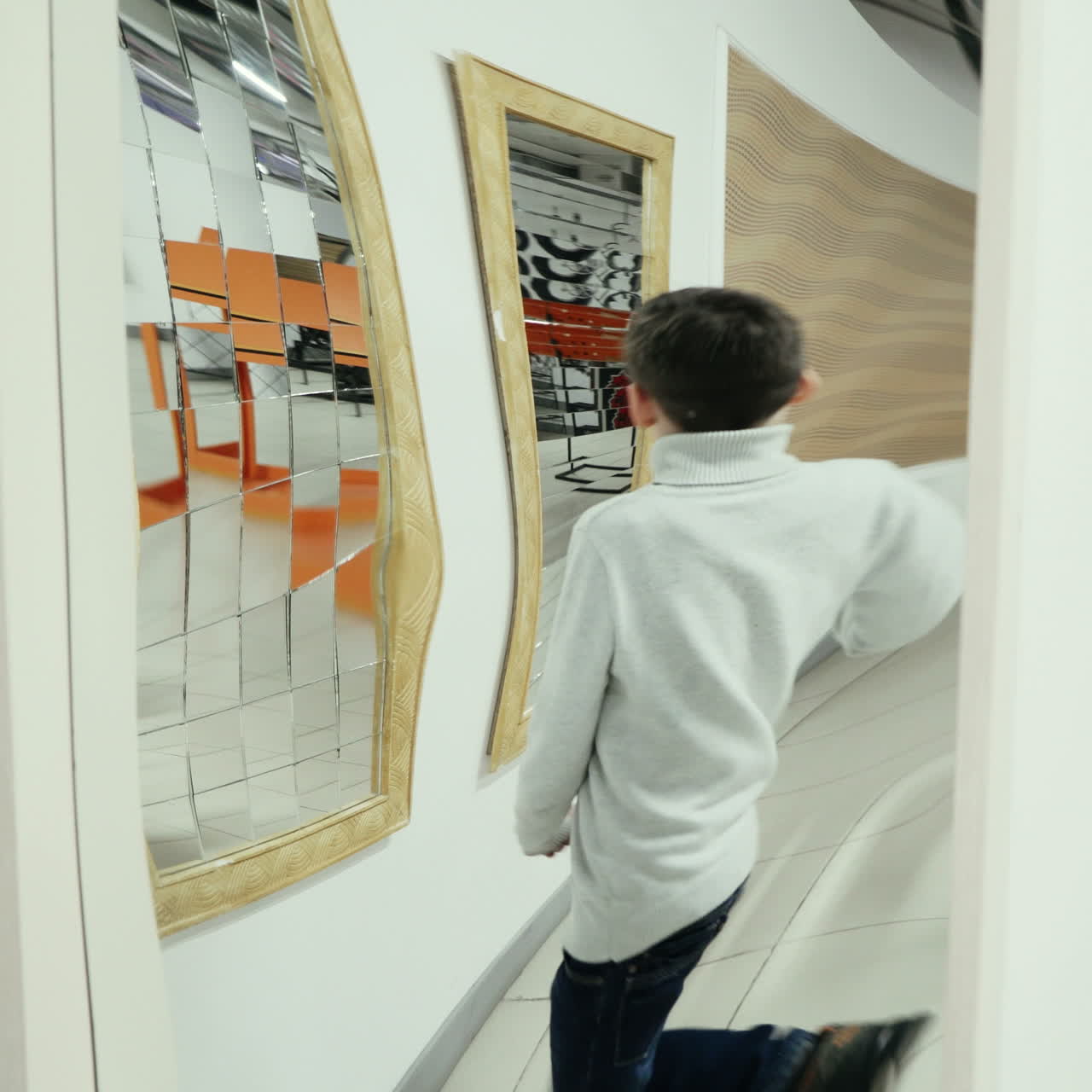 Ragazzo che gioca con uno specchio deformante nel museo della scienza. Video quadrato.