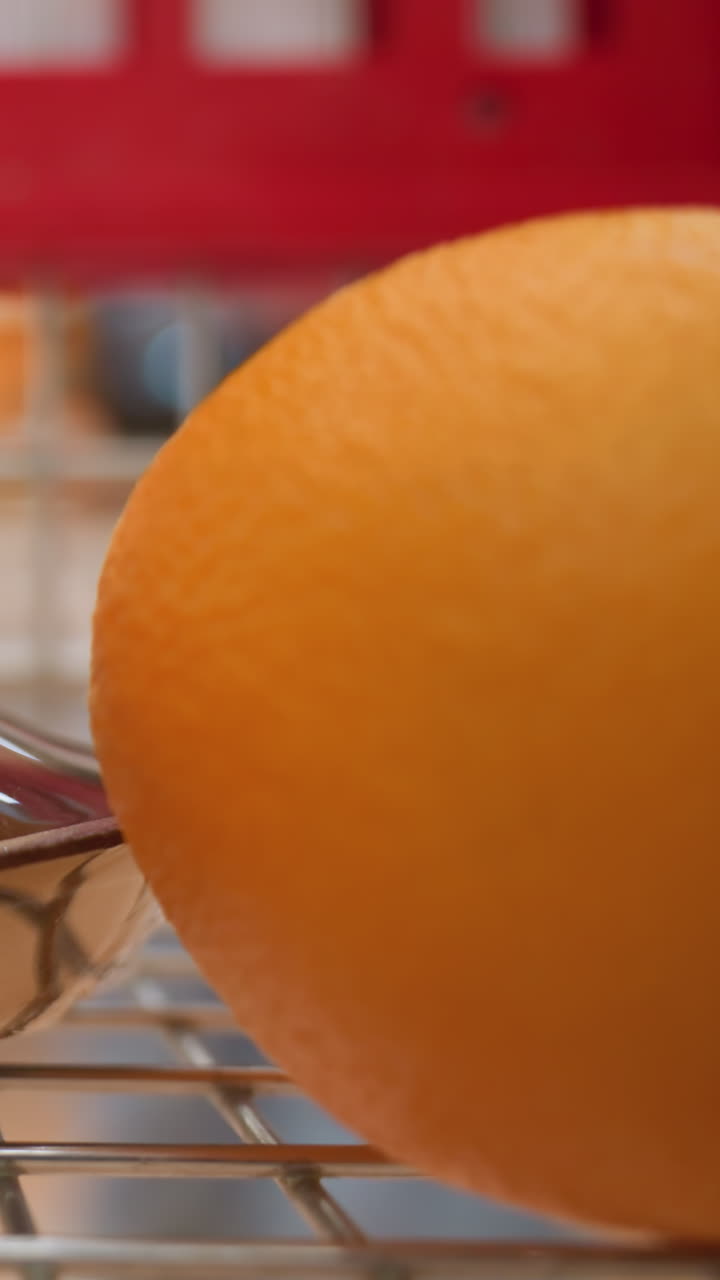 포장된 사과와 오렌지를 쇼핑 트롤리에 넣는 손. 이 장면은 식료품 쇼핑의 행위를 강조하며, 드 헬드 카메라로 촬영하여 역동적이고 몰입력있는 시야를 제공합니다.