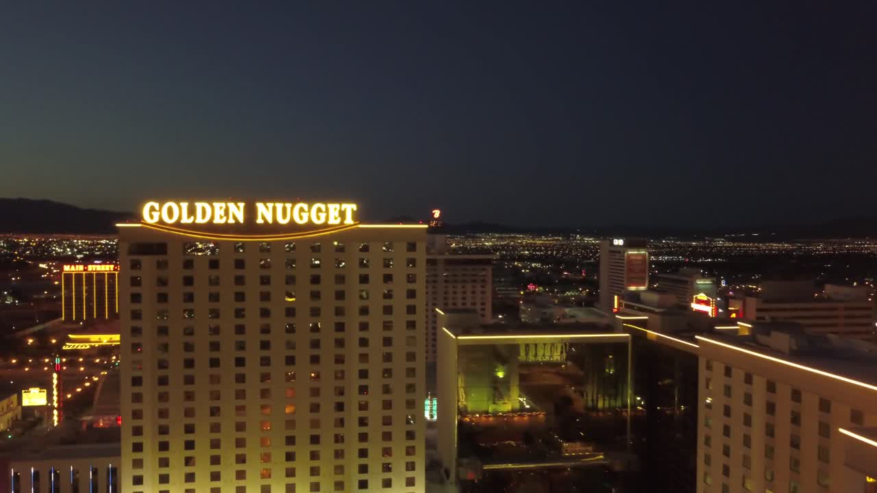 4K AERIAL: Aerial shot backwards from the Golden Nugget Hotel and Casino in Las Vegas to reveal the city lights at dusk