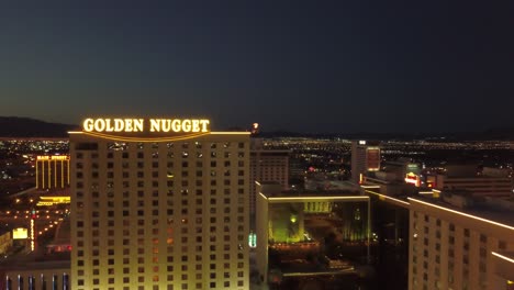 4k aerial: aerial shot backwards from the golden nugget hotel and casino in las vegas to reveal the city lights at dusk