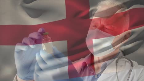 Animation-Der-Flagge-Englands,-Die-über-Einem-Arzt-Winkt,-Der-Eine-Gesichtsmaske-Trägt-Und-Einen-Impfstoff-In-Der-Hand-Hält