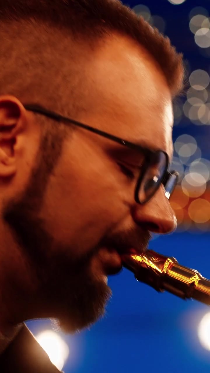 Primo piano di un uomo che suona il sassofono con luci bokeh sullo sfondo