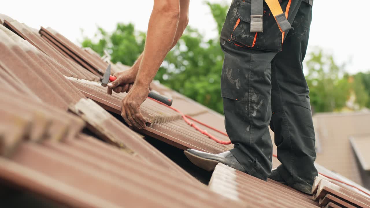 Tuttofare che ripara un tetto con nuove tegole, lavoro in altezza
