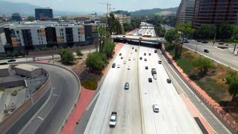 Route-134-freeway-in-Burbank,-California-with-light-traffic-during-daytime---tilt-up-aerial-reveal