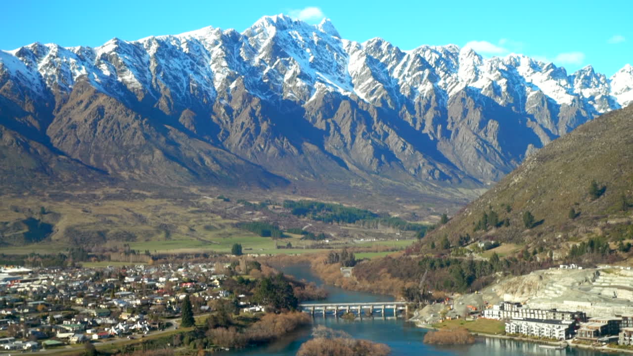 The Remarkable's South Island Queenstown New Zealand snowy mountain peaks green valley aerial drone winter beautiful sunny morning afternoon Lake Wakatipu Wanaka landscape to the left movement
