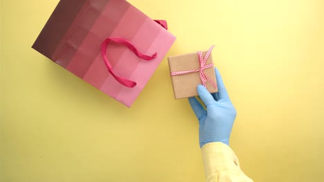 hand in gloves delivering a gift in a shopping bag