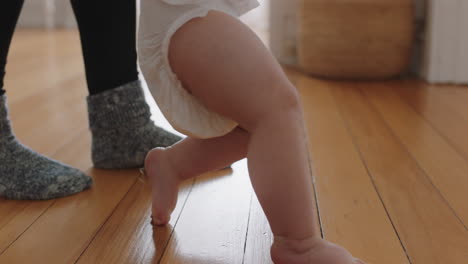 baby learning to walk toddler taking first steps with mother helping infant teaching child at home