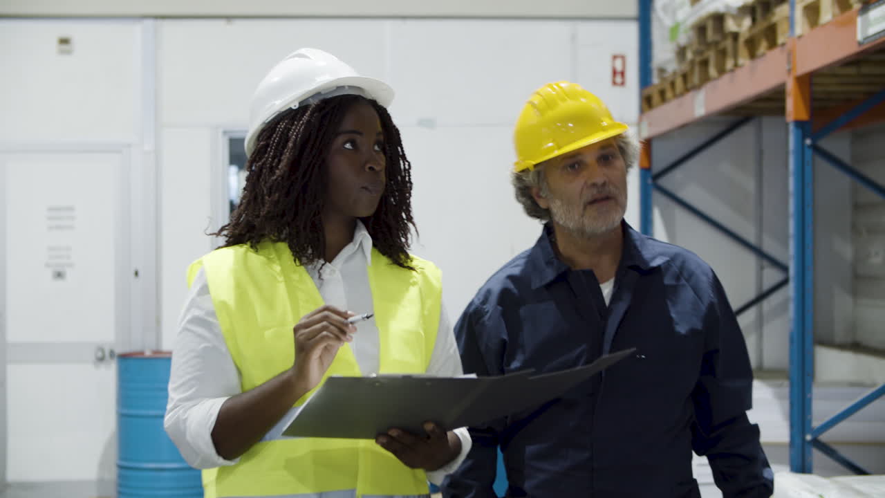 Multiethnic workers in helment walking and counting goods in stock
