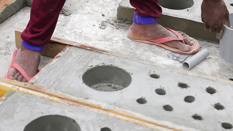 indian mason worker removing pvc pipes from hardened concrete during construction
