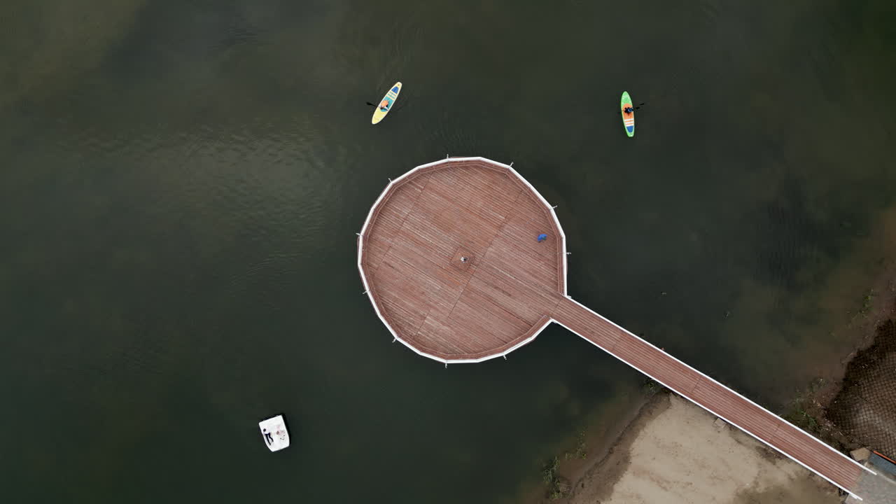 Circular Wooden Pier on a Lake with Paddleboards